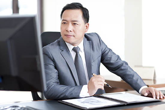 Mature Chinese businessman using computer at desk